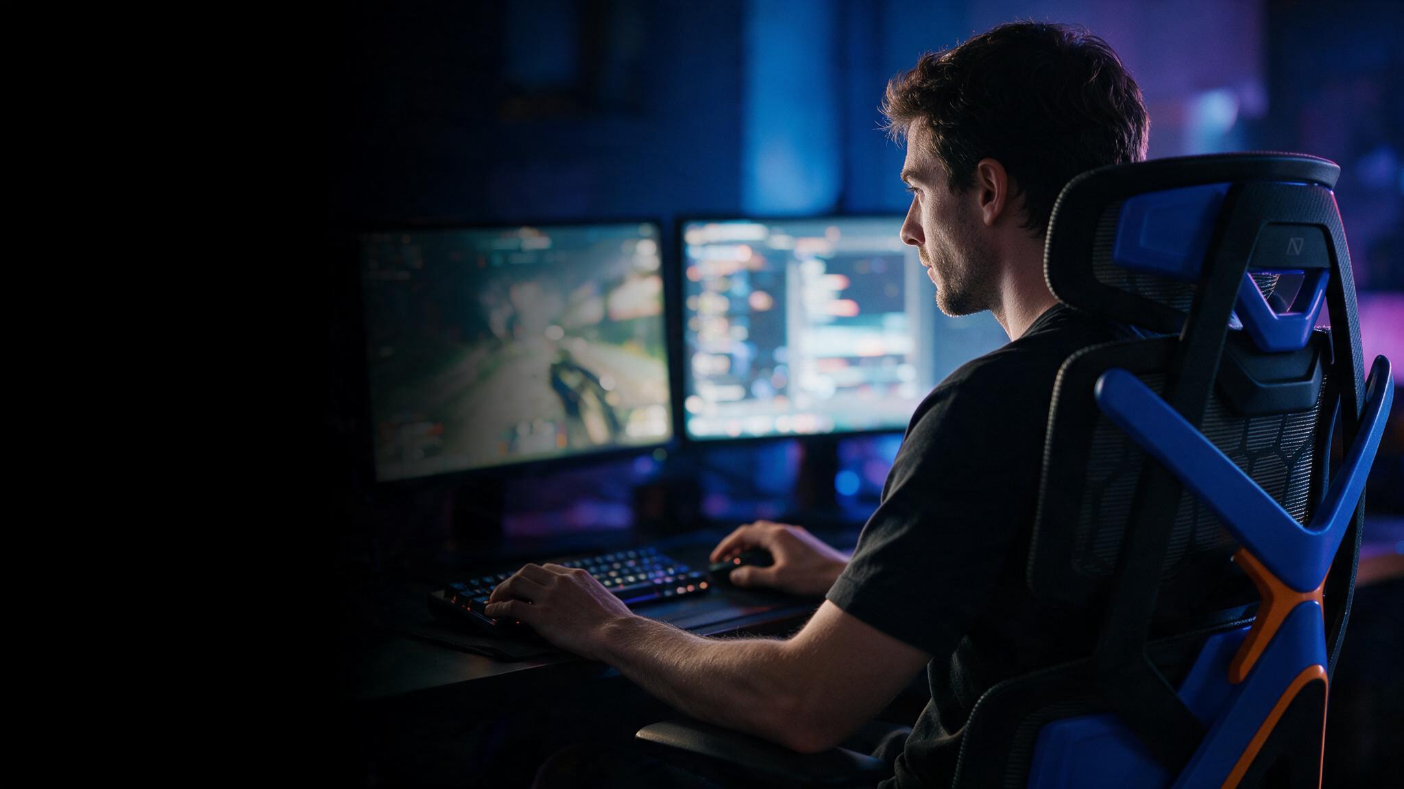 Jogador em partida noturna, sentado na cadeira Vector diante de dois monitores