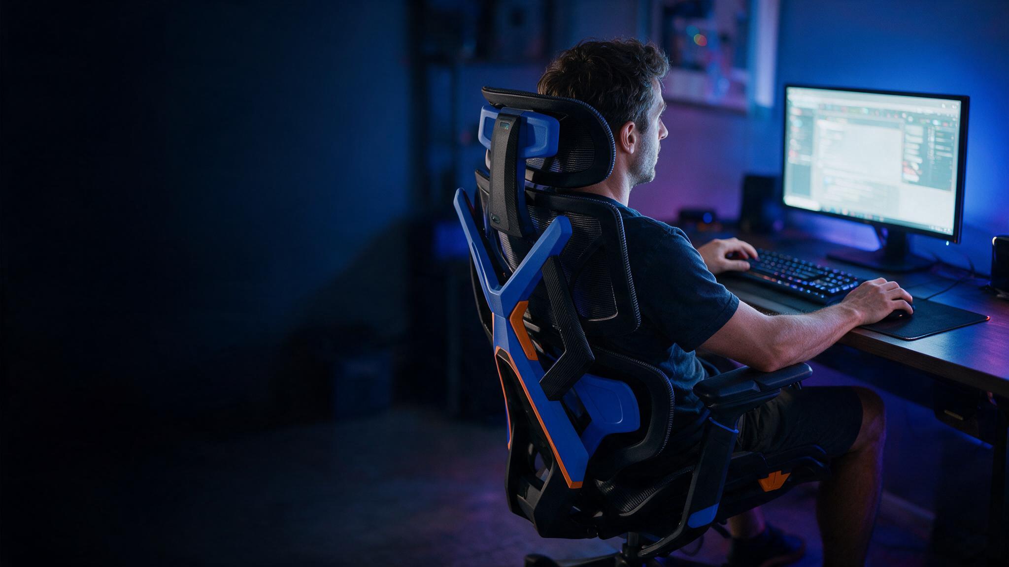 Jogador com o tronco fora do eixo em frente ao monitor, à noite